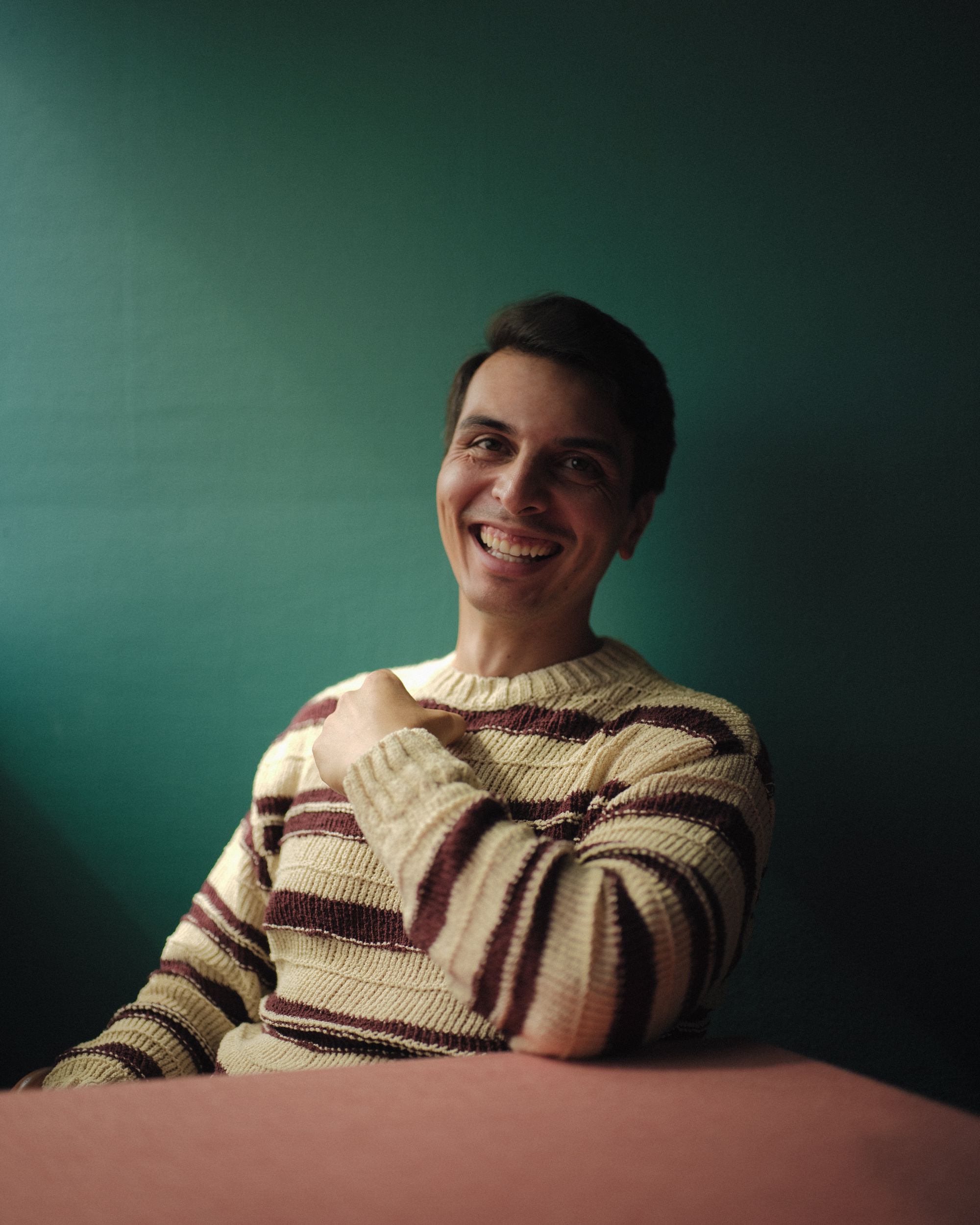 Michael Skellern smiling in a teal-walled room.